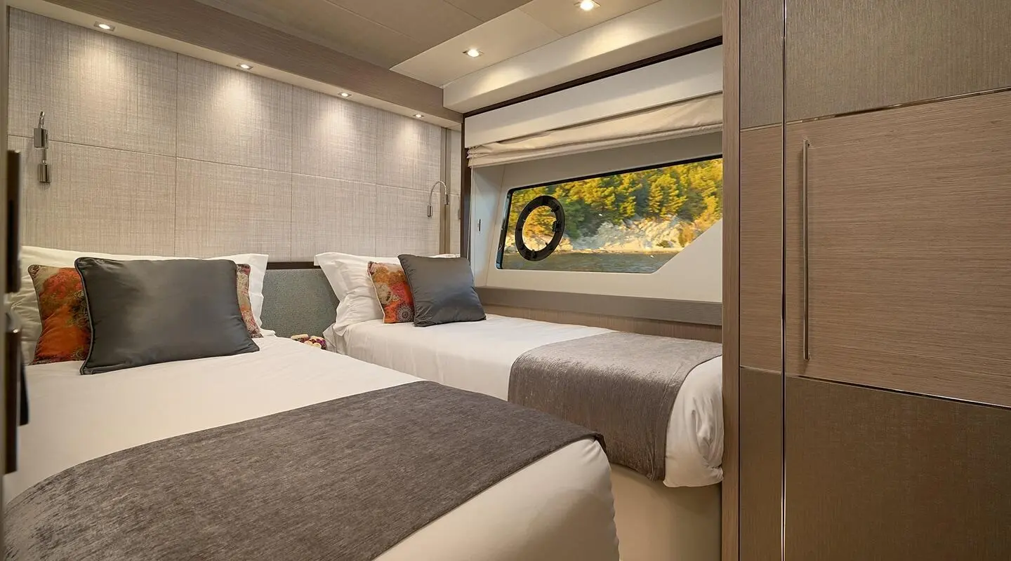 Spacious yacht cabin with two large beds, neutral tones, window view