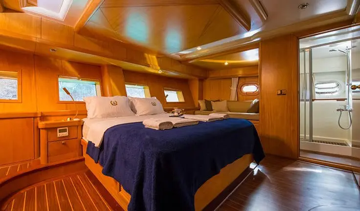 Master cabin with king bed, navy bedding, wood panels, ensuite area
