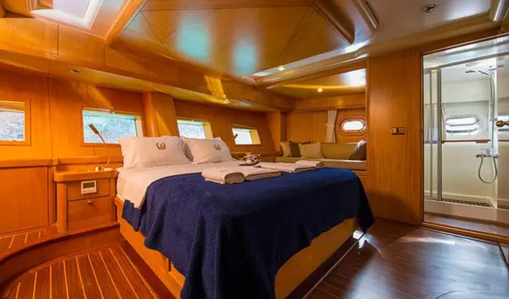 Master cabin with king bed, navy bedding, wood panels, ensuite area