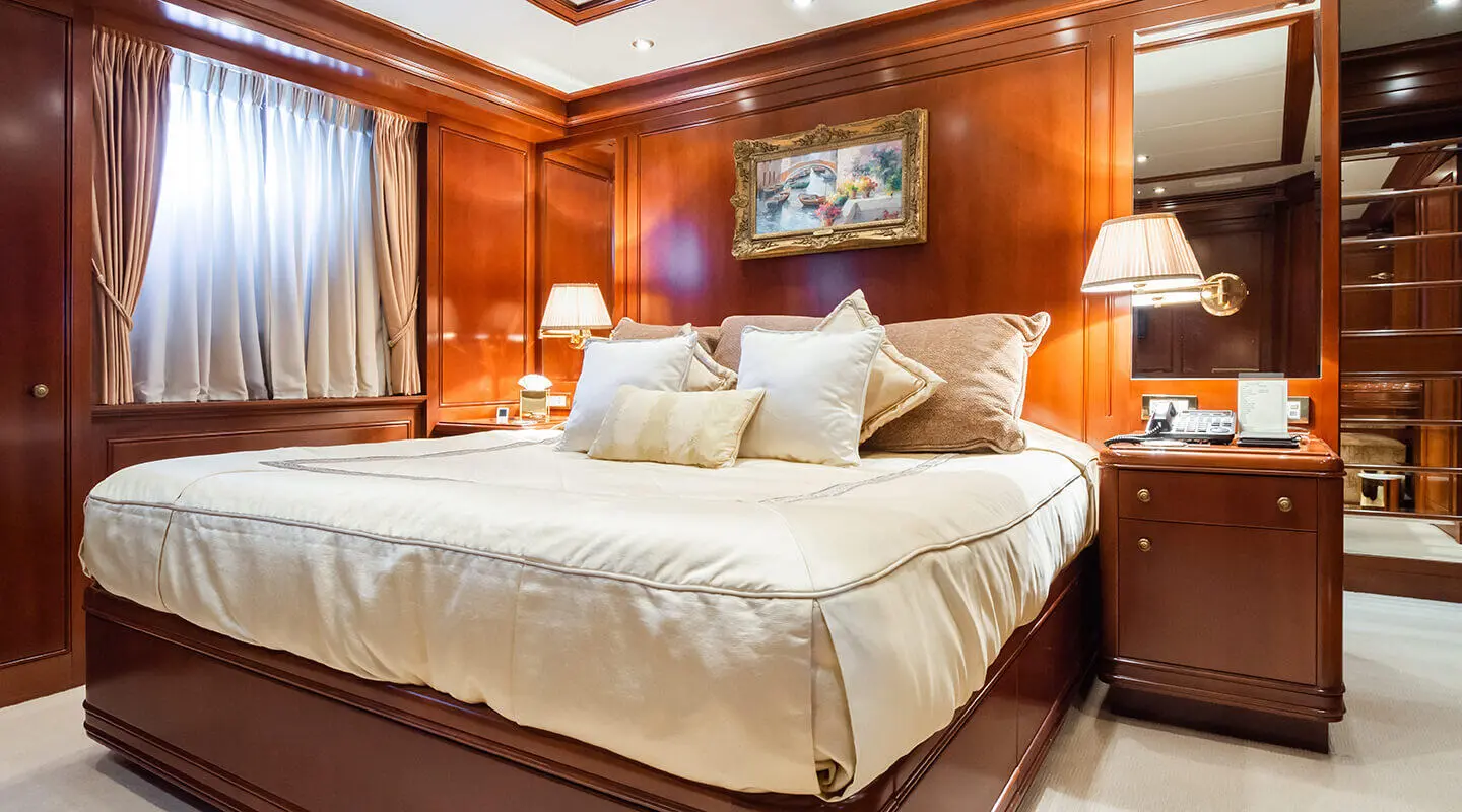 Apogee yacht interior: double cabin with large bed and wooden panels