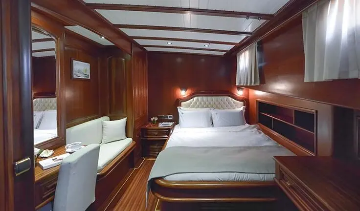 Master cabin with a large bed, wood-paneled walls, and bedside lamps