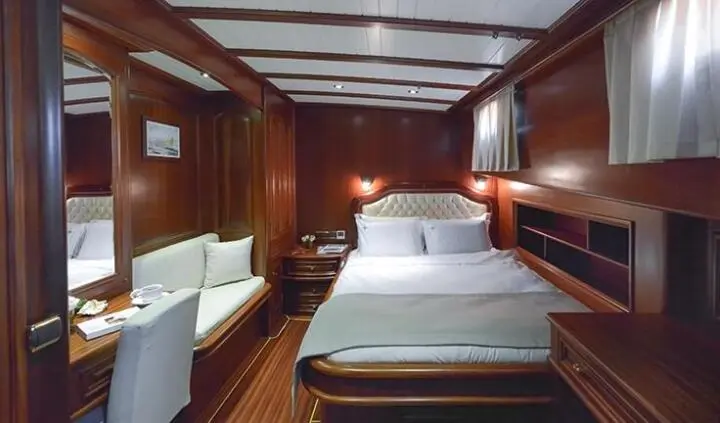 Master cabin with a large bed, wood-paneled walls, and bedside lamps
