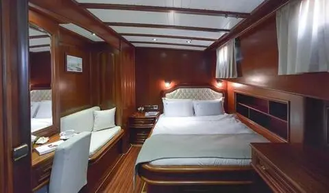 Master cabin with a large bed, wood-paneled walls, and bedside lamps