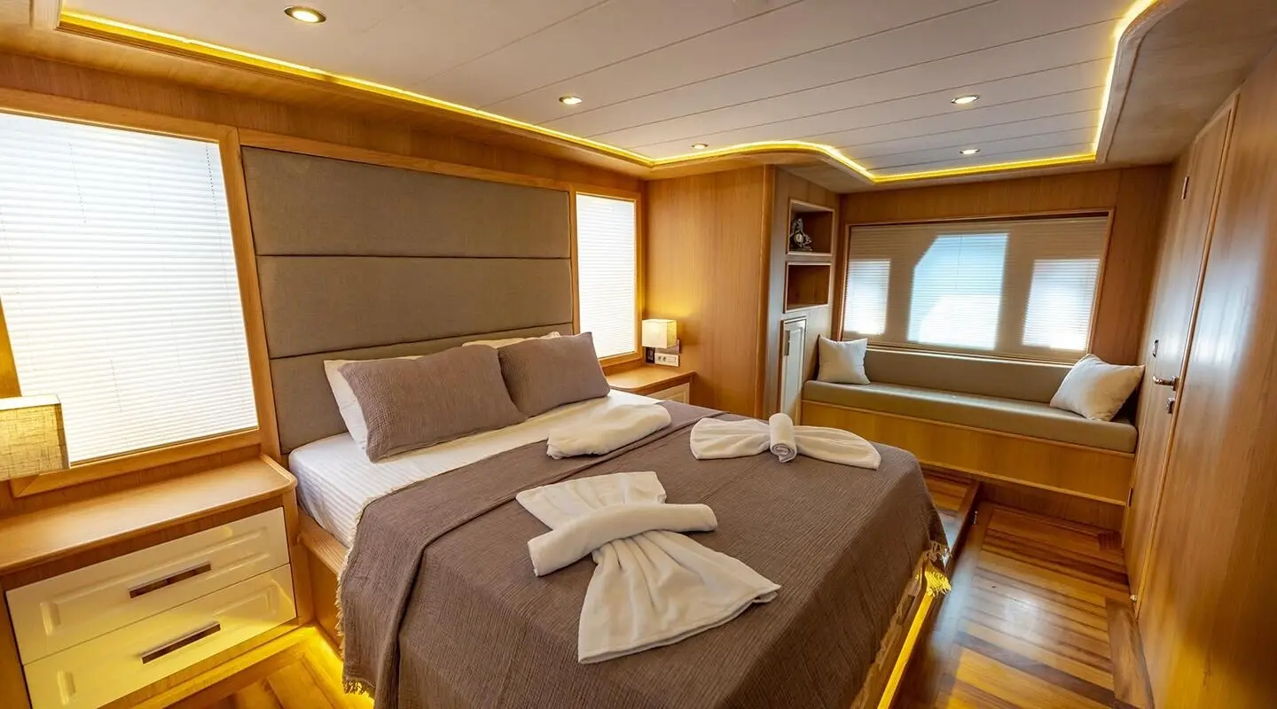 Luxurious yacht bedroom with two large beds, brown bedding, and warm lighting