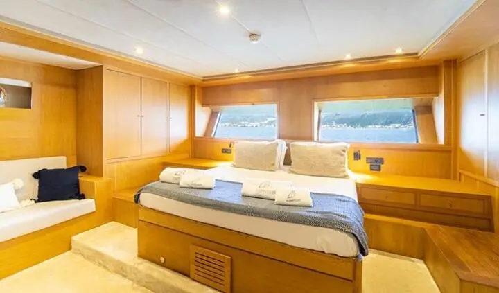 Master cabin with king bed, white and blue bedding, wood paneling, ensuite doorway