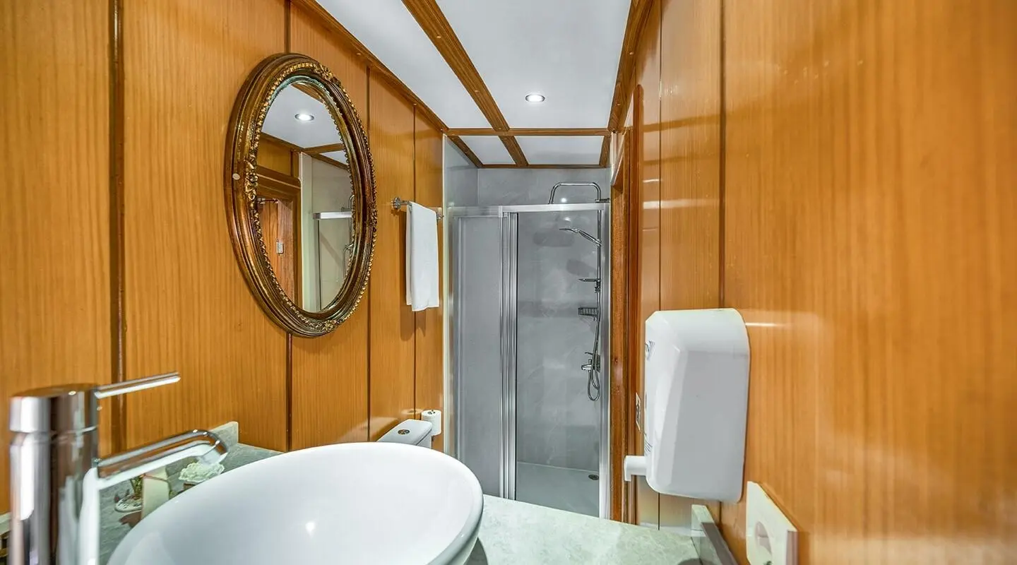 Interior of a yacht with wooden walls, round window, and white fixtures