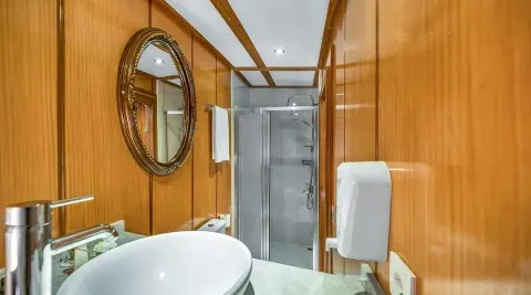 Interior of a yacht with wooden walls, round window, and white fixtures