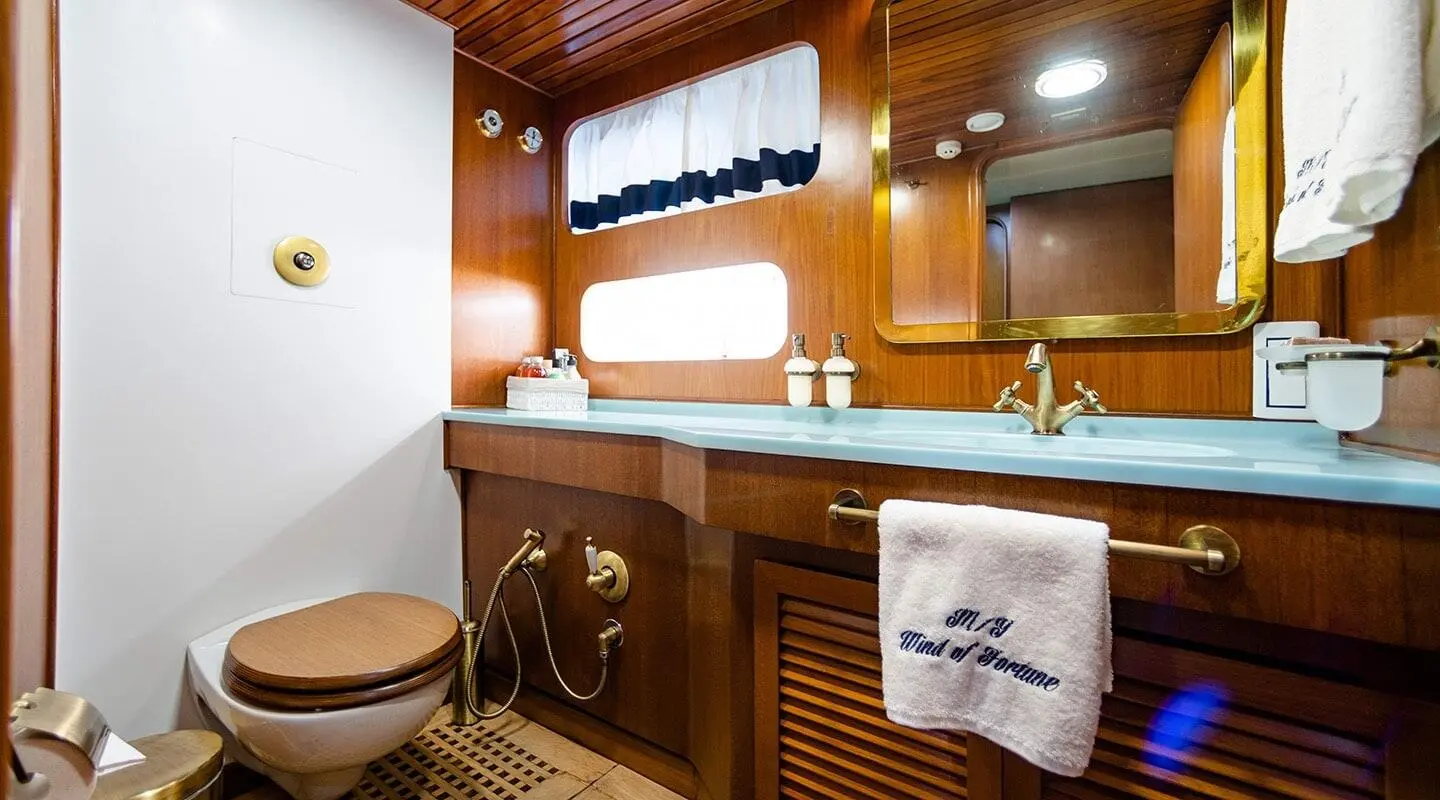 Luxurious yacht Wind Of Fortune deck with polished wood, window, and sink area at sunset