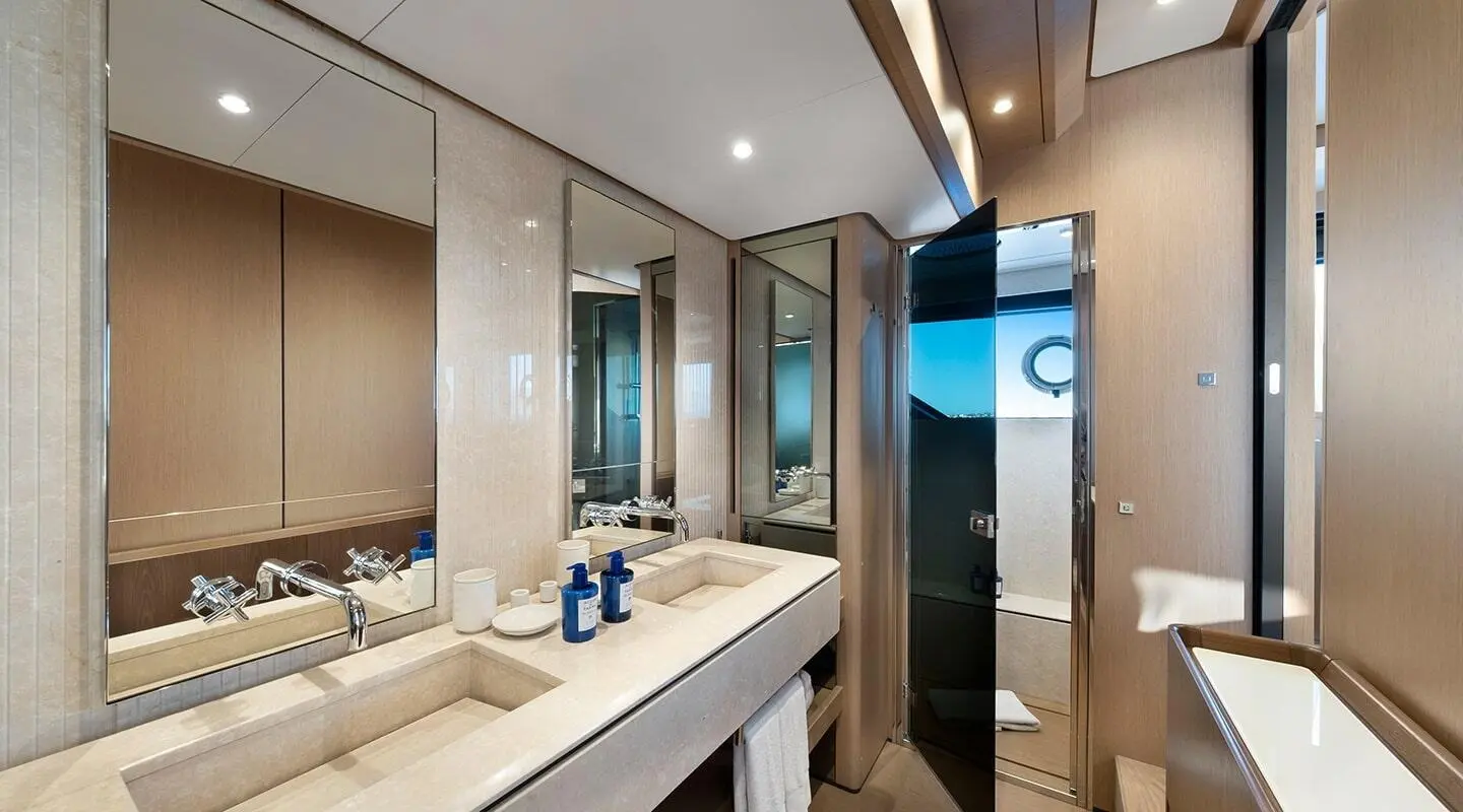 Spica yacht bathroom with twin sinks, large mirror, and beige decor