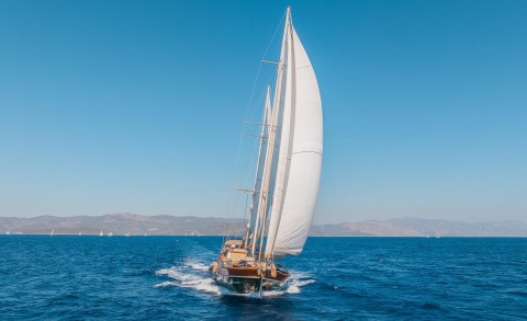 Sailing yacht with large white sails on blue sea horizon