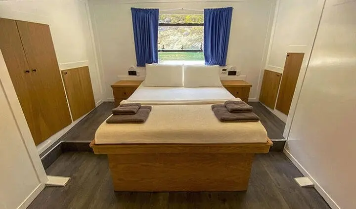 Master cabin with king bed, blue drapes, wooden furnishings, ensuite implied