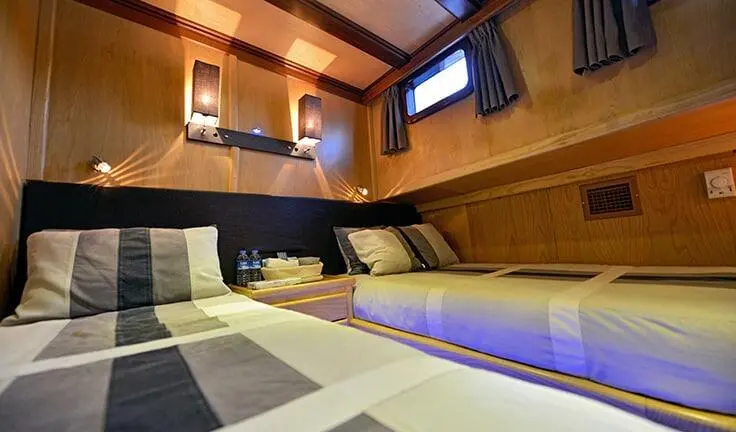 Interior cabin with twin beds, soft lighting, and wood paneling on Derin Deniz yacht