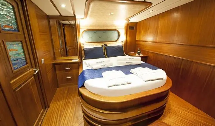 Master cabin with king bed, wood panelling, and ensuite in warm lighting