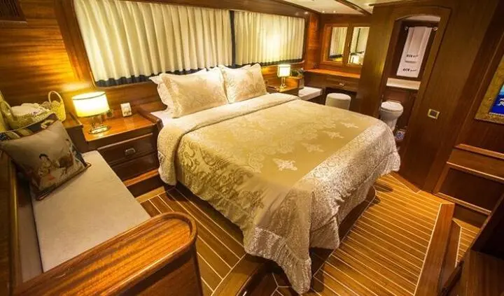 Master cabin with king bed, beige linens, wooden panels, bedside lamps