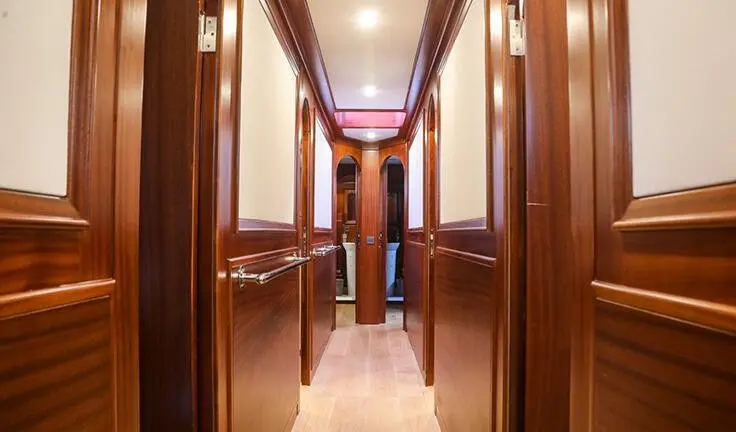 Elegant yacht cabin corridor with polished wood panels and soft lighting aboard Ulucinar