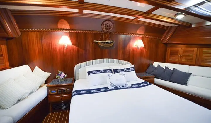 Master cabin with king bed and wood paneling, bedside lamps, and porthole windows