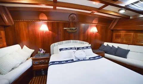 Master cabin with king bed and wood paneling, bedside lamps, and porthole windows