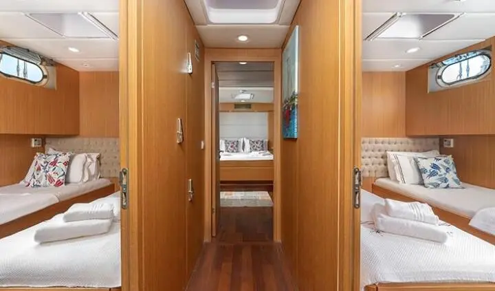 Interior of Artemis Gulet cabin with wooden panels, narrow doorway, shelves, and bunk bed area