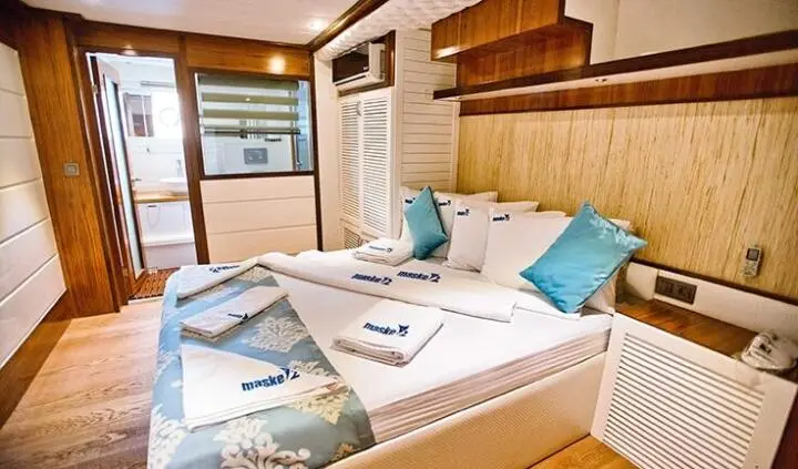 Maske 2 master cabin interior with bed, pillows, and wooden shelves