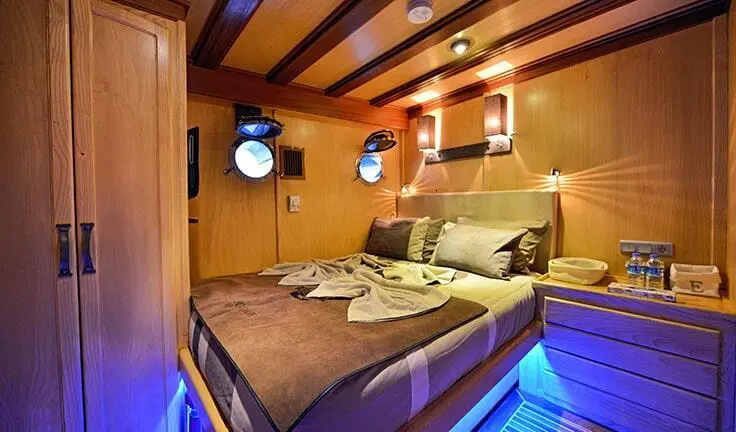 Master cabin with a large bed, wood paneling, and ensuite doorway on yacht