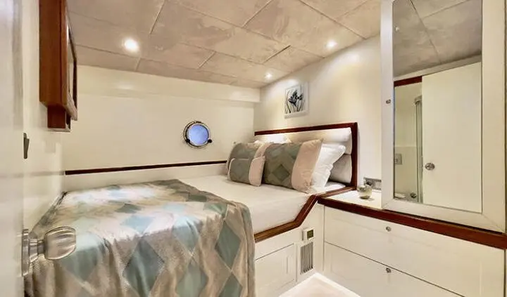 Cozy yacht cabin with two beds, wooden cabinets, and soft lighting