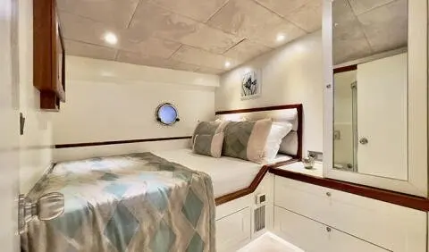 Cozy yacht cabin with two beds, wooden cabinets, and soft lighting