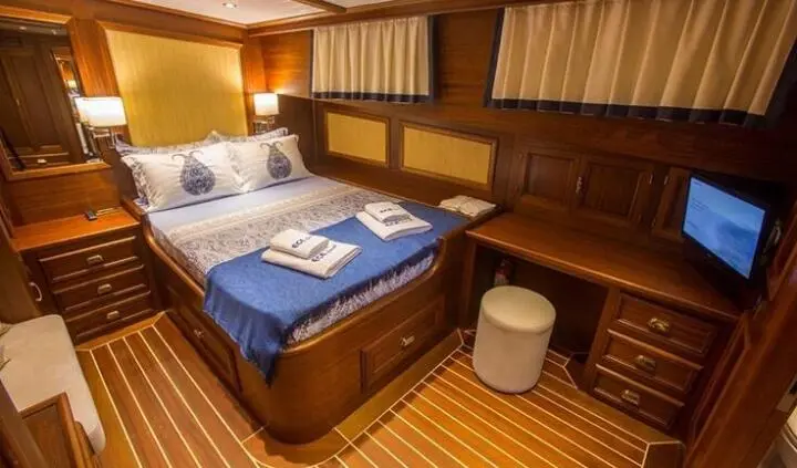 Two single berths with blue and white bedding in a wood-paneled cabin