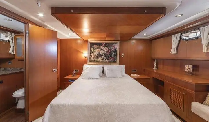 Arabella cabin bedroom with white bed, wooden walls, bedside lamps