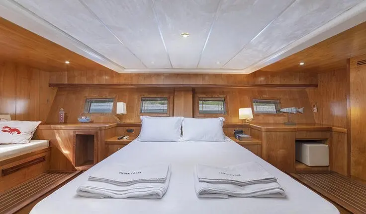 Queen Of Sea master cabin with king bed, white linens, wood paneling, ceiling lights