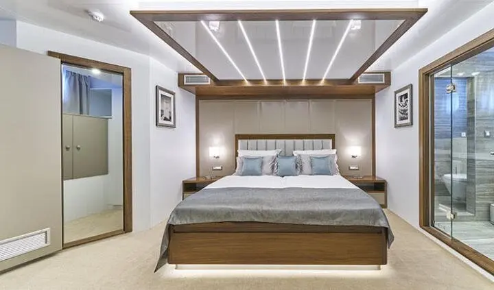 Double bed with upholstered headboard and bedside tables in a stylish yacht cabin