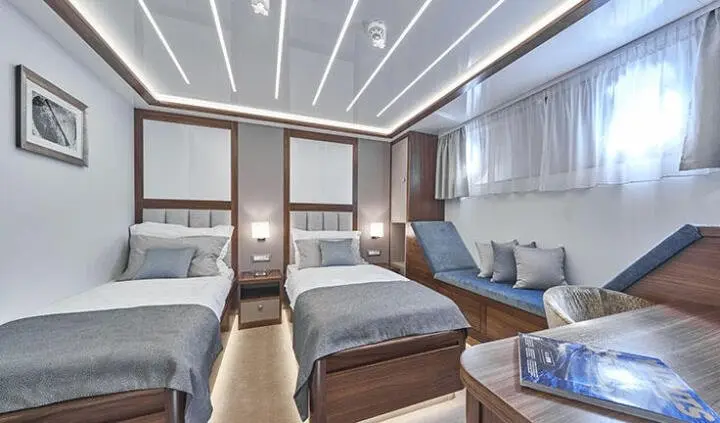 Interior of Corsario yacht cabin with twin beds, seating, and wood paneling
