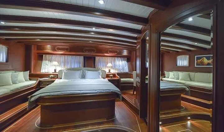 Master cabin with two beds, wooden beams, and ensuite area visible
