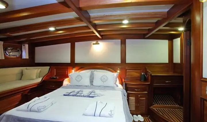 Master cabin with king bed, white linens, wooden headboard and built-in nightstands