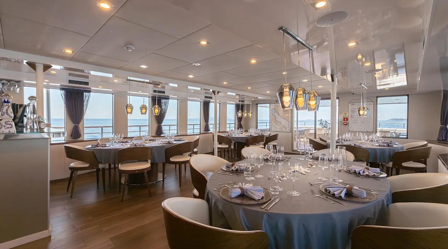 Yolo luxury yacht dining area with round table settings and warm lighting