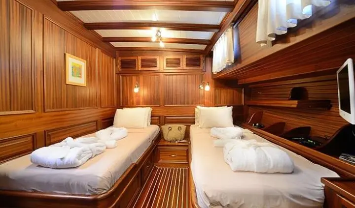 Twin cabin aboard Zephyria II with two single beds and wooden walls