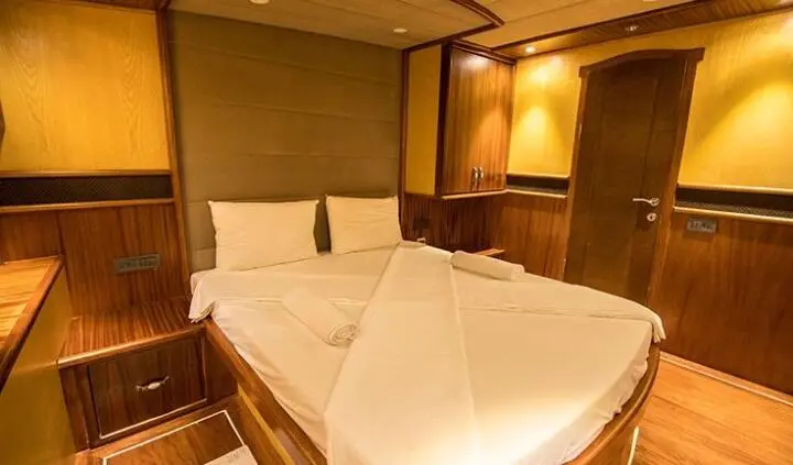 Nevra Queen yacht cabin with a double bed, white linens, wood paneling