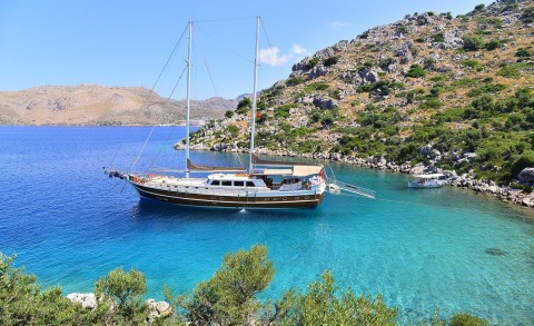 Gullet Prenses Bugce anchored in a turquoise cove with rocky hillside
