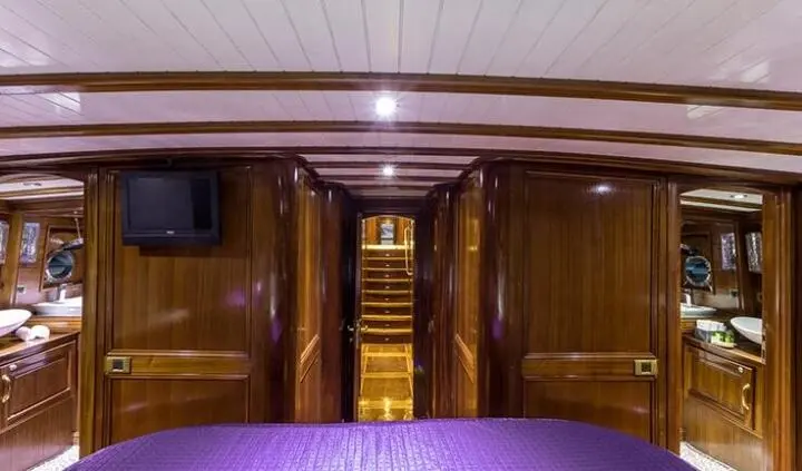 Luxurious yacht cabin with king bed, wooden paneling, and ensuite door