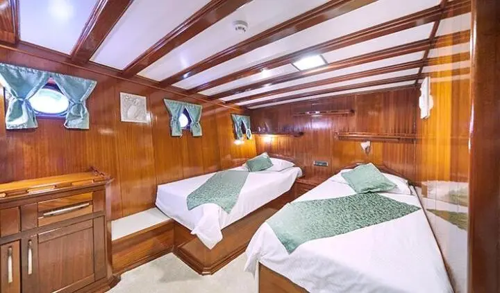 Stella Maris yacht cabin with two twin beds, wooden paneling, and bedding