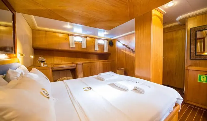 Interior of a yacht cabin with two bunk beds, wood panels, and compact seating