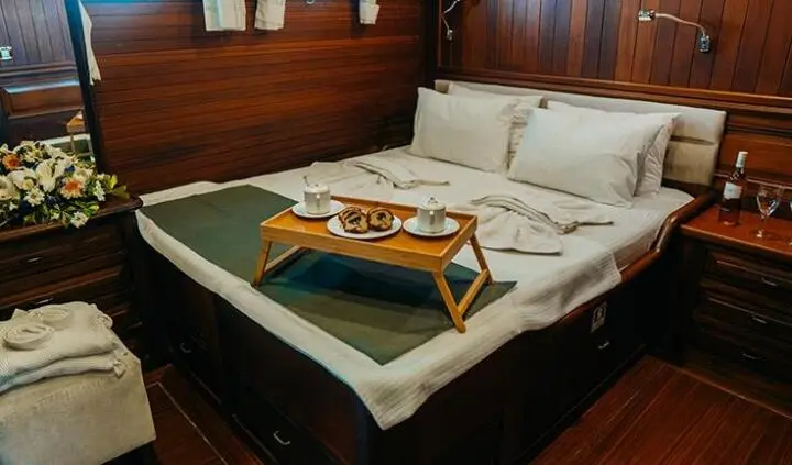 Cozy cabin with large bed, wooden panels, and a breakfast tray on the bed