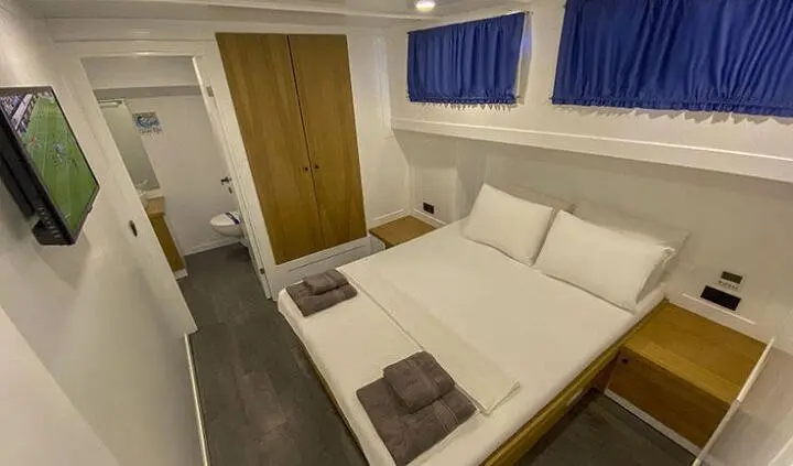 Maske 5 master cabin with king bed, white bedding, two pillows, wood headboard