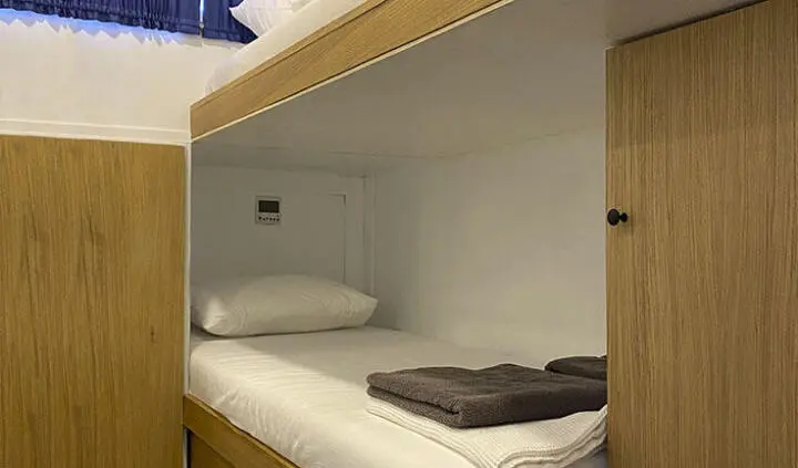 Maske 5 cabin bed with white bedding and a gray folded blanket