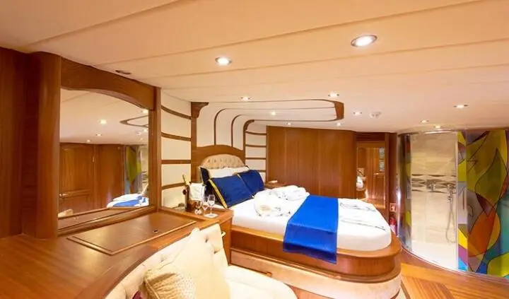 Master cabin with wooden panels, two single beds, blue bed runners, and bedside lamps