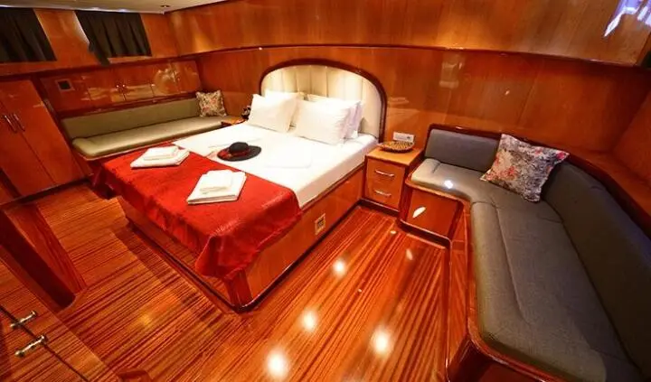 Maya yacht guest cabin with queen bed, wood paneling, and seating area