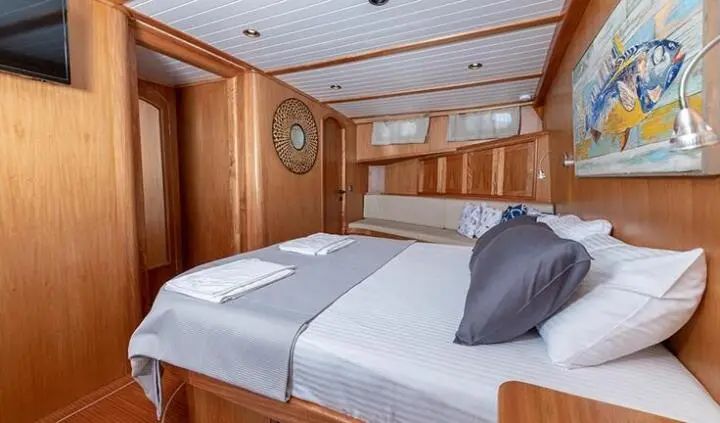Master cabin with two single beds pushed together, wooden walls and ceiling