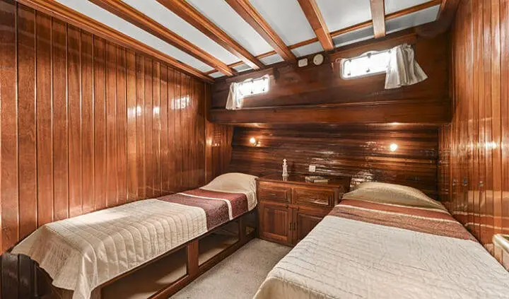 Two twin wooden cabins with built-in bunks and rounded porthole windows
