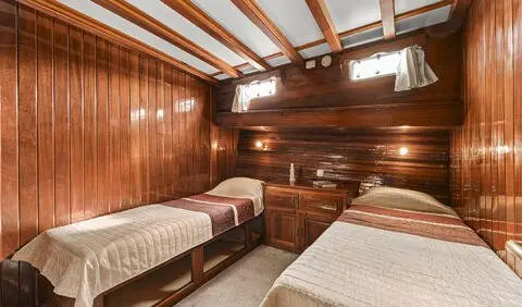 Two twin wooden cabins with built-in bunks and rounded porthole windows