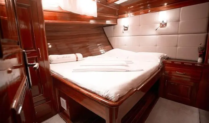 Master cabin with king bed, white linens, wood accents, ensuite door