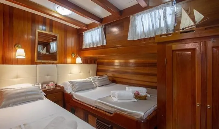 Andi Star cabin with triple-bed setup, wood paneling, window curtains, and built-in seating